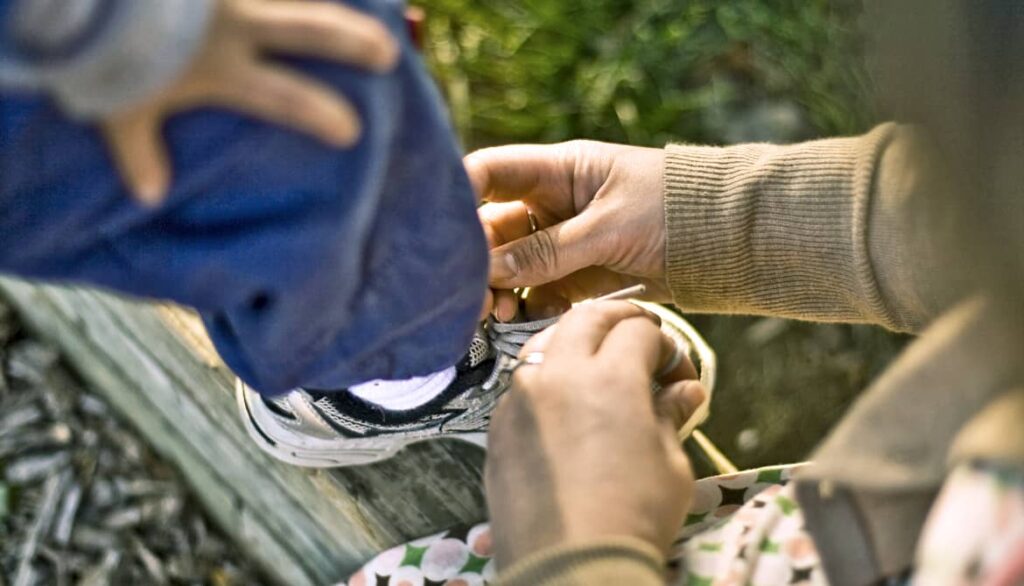 Madre ayudando a ponerse los zapatos a su hijo